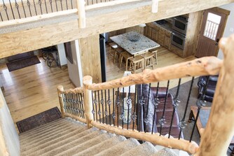 Log railing staircase overlooking kitchen and dining